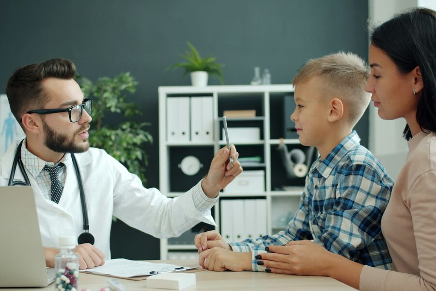 Medic care discută cu un băiat și cu mama lui, în cabinet